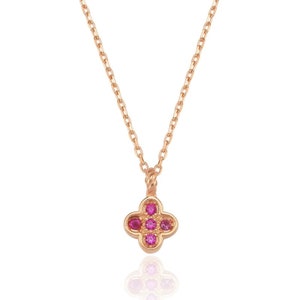 Peut inclure: Un collier délicat en or avec un petit pendentif en forme de trèfle à quatre feuilles orné de pierres précieuses roses.