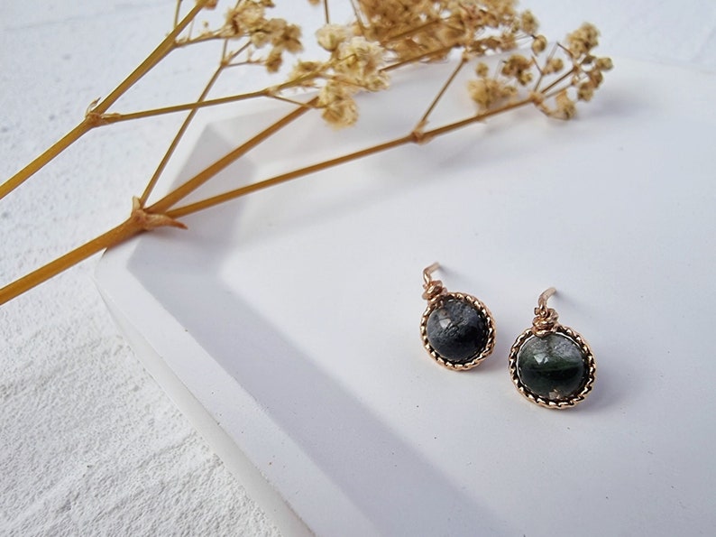 May include: A pair of earrings with a dark green and black stone set in a gold wire frame.