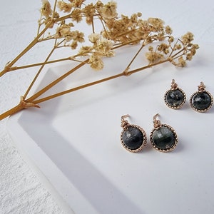 May include: A pair of dangle earrings with black and green gemstone cabochons set in gold-toned wire.