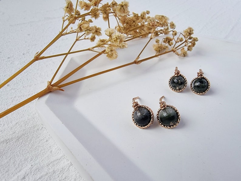May include: A pair of dangle earrings with black and green gemstone cabochons set in gold-toned wire.