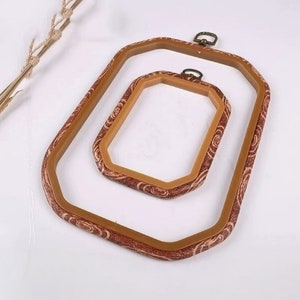 May include: Two brown embroidery hoops with a decorative pattern. The larger hoop is 25 cm in diameter and the smaller hoop is 15 cm in diameter.