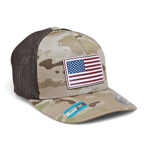 Puede incluir: Una gorra de béisbol de camuflaje con la parte trasera de malla marrón y una visera curva. La gorra presenta un parche rectangular con la bandera estadounidense. El sombrero tiene una etiqueta MultiCam.
