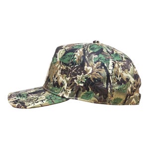 May include: A camouflage baseball cap with a pattern of green, brown, and beige foliage. The cap has a curved peak and a structured crown. The hat is designed for outdoor activities and provides sun protection.