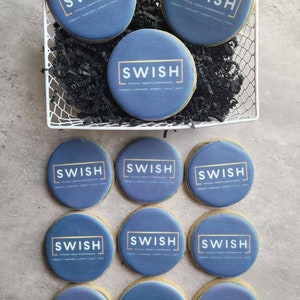 May include: A dozen round blue cookies with gold lettering that reads "SWISH PHYSICAL THERAPY & PERFORMANCE" in a white box with black shredded paper.