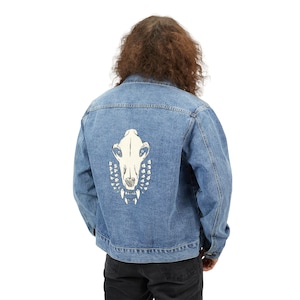 May include: A blue denim jacket with a white embroidered skull design on the back.