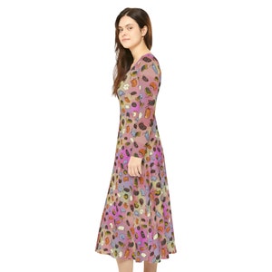 Puede incluir: Un vestido de manga larga con un fondo degradado rosa, morado y amarillo. El vestido está cubierto de un patrón de pequeñas ilustraciones coloridas de varios insectos.