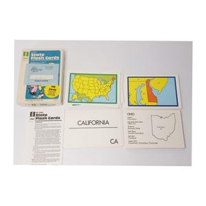 May include: A set of vintage "State Flash Cards" with a box and individual cards. The box features the text "100 Cards" and "State Flash Cards". The cards include state maps, state names, and facts. The California card is visible.