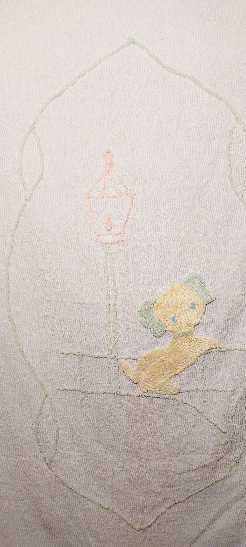 May include: A white crocheted baby blanket with a light pink lamppost and a yellow dog embroidered on it.