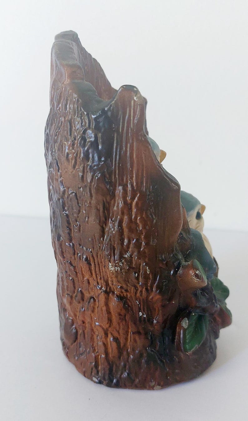 May include: A ceramic figurine of two bluebirds perched on a tree stump. The stump is brown and has a rough texture. The birds are painted in shades of blue and white.