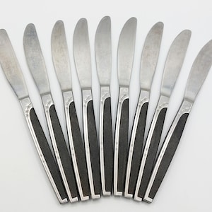 May include: Set of ten silver dinner knives with black handles. The knives have a simple, modern design.