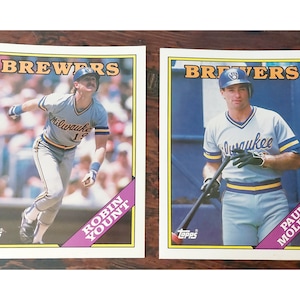 May include: Two baseball cards featuring players from the Milwaukee Brewers. The card on the left features Robin Yount, and the card on the right features Paul Molitor.