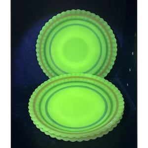 May include: Three green glass plates with a scalloped edge and a concentric circle design in brown, green, and blue.