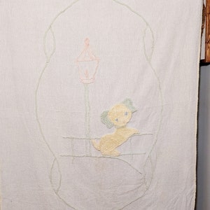 May include: A white quilted baby blanket with a green embroidered frame and a yellow embroidered puppy standing under a pink lamppost.