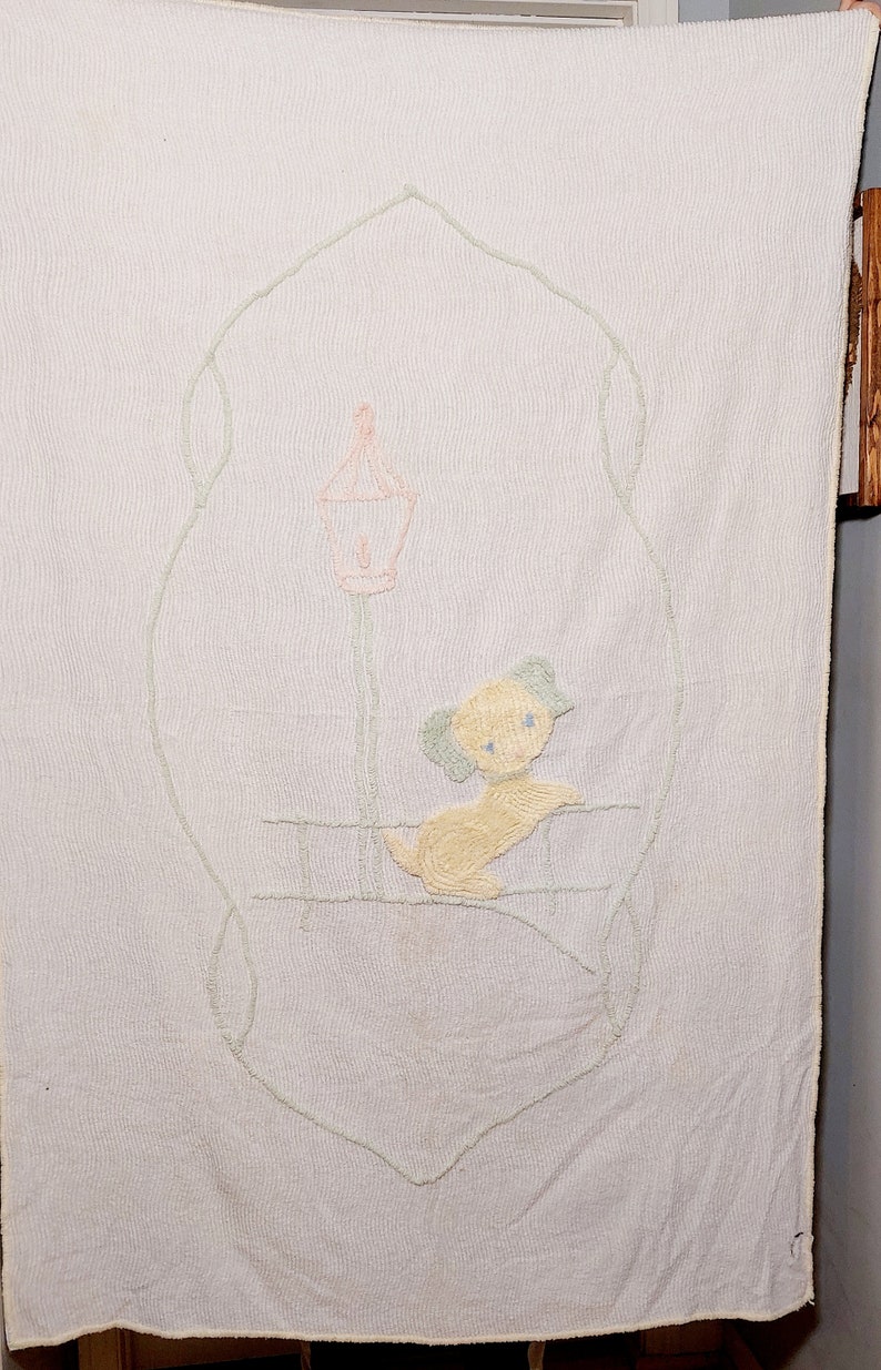 May include: A white quilted baby blanket with a green embroidered frame and a yellow embroidered puppy standing under a pink lamppost.