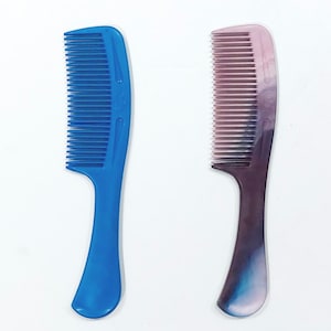 May include: Two plastic hair combs. One is a solid blue, the other is a gradient of pink, purple, and blue. Both combs have a handle and closely spaced teeth for detangling hair.