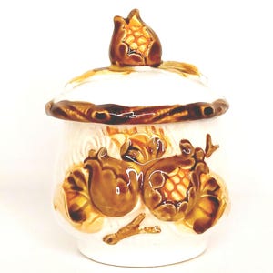 May include: White ceramic sugar bowl with a brown lid and brown corncob designs. The lid has a single corncob on top.