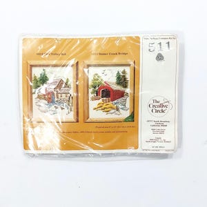 May include: A cross-stitch kit featuring two framed landscape scenes: "Valley Mill" and "Stoney Creek Bridge." The finished size is 8" x 10" (20.3 cm x 25.4 cm). The package includes fabric, wood, yarn, needle, and instructions.