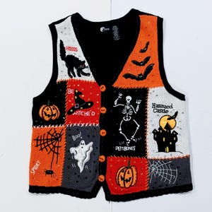 May include: A black, orange, and white Halloween-themed vest with various embroidered patches. The patches feature a black cat, bats, a skeleton, a haunted castle, pumpkins, a spider web, and the words "HISSSS", "BE WITCHED", "Boo!", and "DEMBONES".