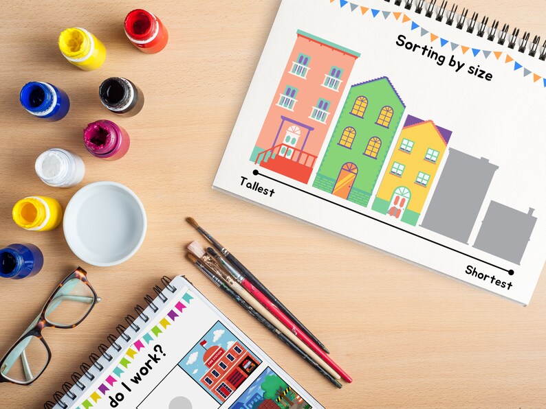 May include: A worksheet with a line of colorful houses of different sizes, labeled "Tallest" and "Shortest".  The worksheet is on a wooden table with paint bottles, paintbrushes, and a bowl.  The text "Sorting by size" is at the top of the worksheet.