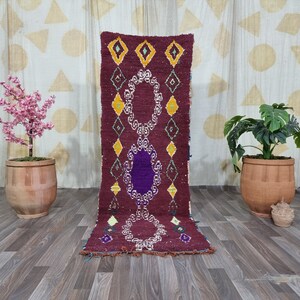 May include: A rectangular runner rug in deep burgundy wool featuring a central vertical column of three large oval medallions with white intricate borders and a solid purple center, surrounded by smaller yellow and green diamond shapes.