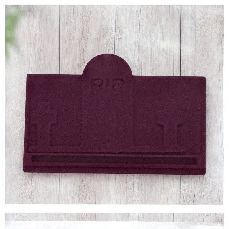 Puede incluir: Un objeto en forma de l&aacute;pida de color burdeos con las letras "RIP" grabadas en la parte superior. El dise&ntilde;o incluye dos cruces y una base rectangular. El art&iacute;culo es probablemente una pieza decorativa o un suministro artesanal.