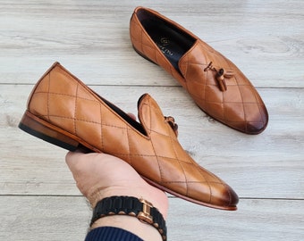 May include: A pair of brown leather loafers with a quilted pattern and tassel detail. The loafers have a brown leather sole and are made of high-quality leather.
