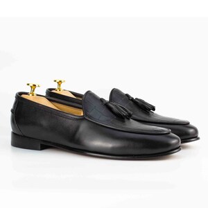 May include: Black leather tassel loafers with a crocodile-embossed pattern on the toe.