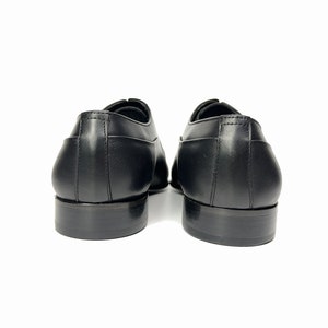 May include: A pair of black leather lace-up shoes with a classic design. The shoes have a rounded toe and a low heel.
