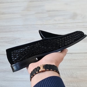 May include: Black velvet loafers with a black beaded design.