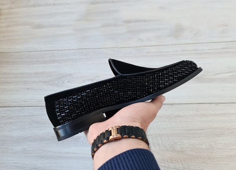 May include: Black velvet loafers with a black beaded design.