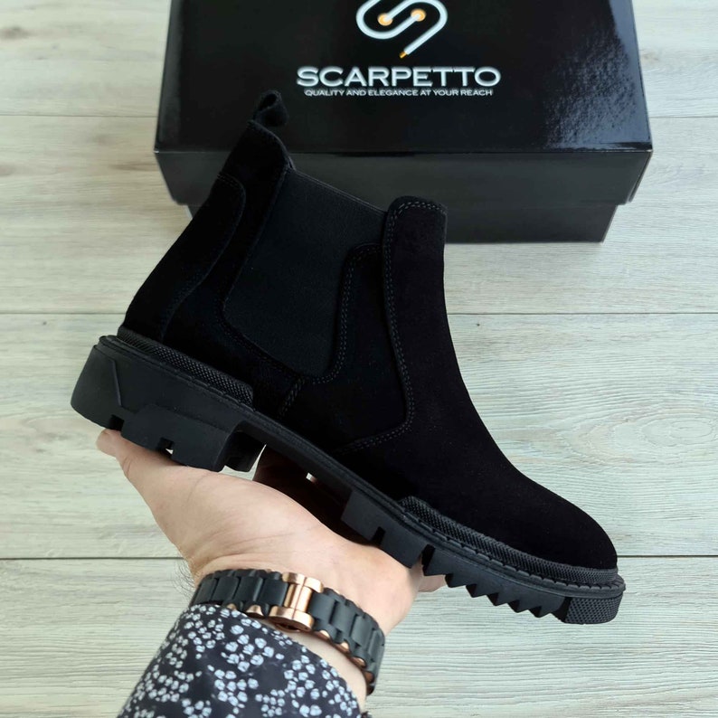 Peut inclure: Bottines Chelsea en daim noir avec une &eacute;paisse semelle en caoutchouc. Les bottes ont un design &agrave; enfiler et un bout l&eacute;g&egrave;rement pointu. Le nom de la marque "Scarpetto" est imprim&eacute; sur la bo&icirc;te.