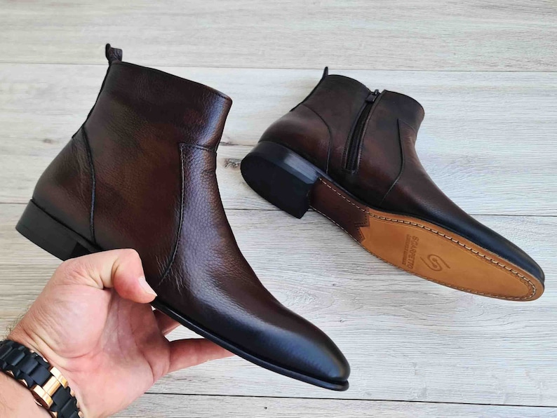 Puede incluir: Un par de botines de cuero marr&oacute;n con cremallera lateral. Los botines tienen punta puntiaguda y tac&oacute;n bajo.