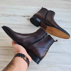 Puede incluir: Un par de botines de cuero marr&oacute;n con cremalleras laterales. Los botines tienen una punta puntiaguda y un tac&oacute;n bajo.