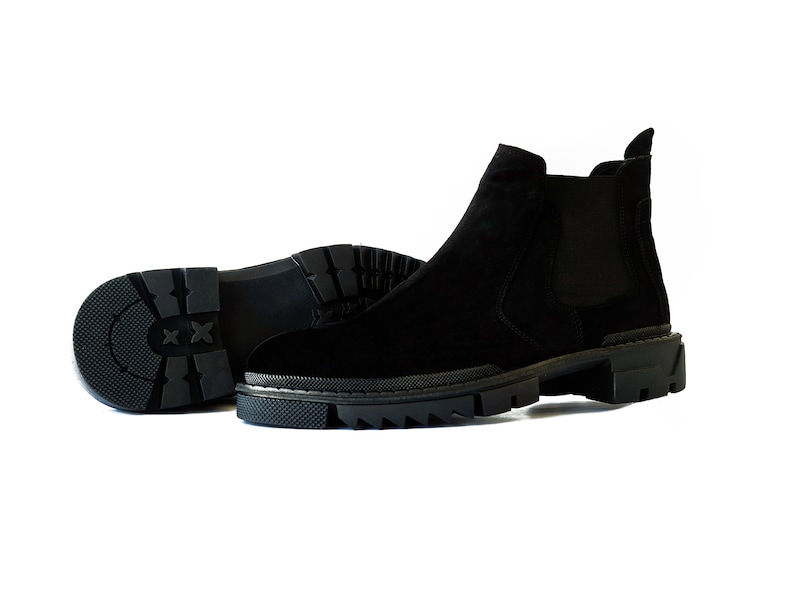 Peut inclure: Une paire de bottines Chelsea en daim noir avec une semelle en caoutchouc &eacute;paisse. Les bottines ont des panneaux lat&eacute;raux &eacute;lastiques et une languette de traction &agrave; l'arri&egrave;re.
