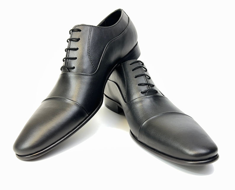 May include: A pair of black leather lace-up shoes with a cap toe design.