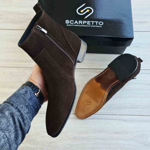Puede incluir: Botas de tobillo de ante marr&oacute;n con cremallera lateral y suela de goma negra. Las botas est&aacute;n fabricadas por Scarpetto, una marca que destaca por su calidad y elegancia.