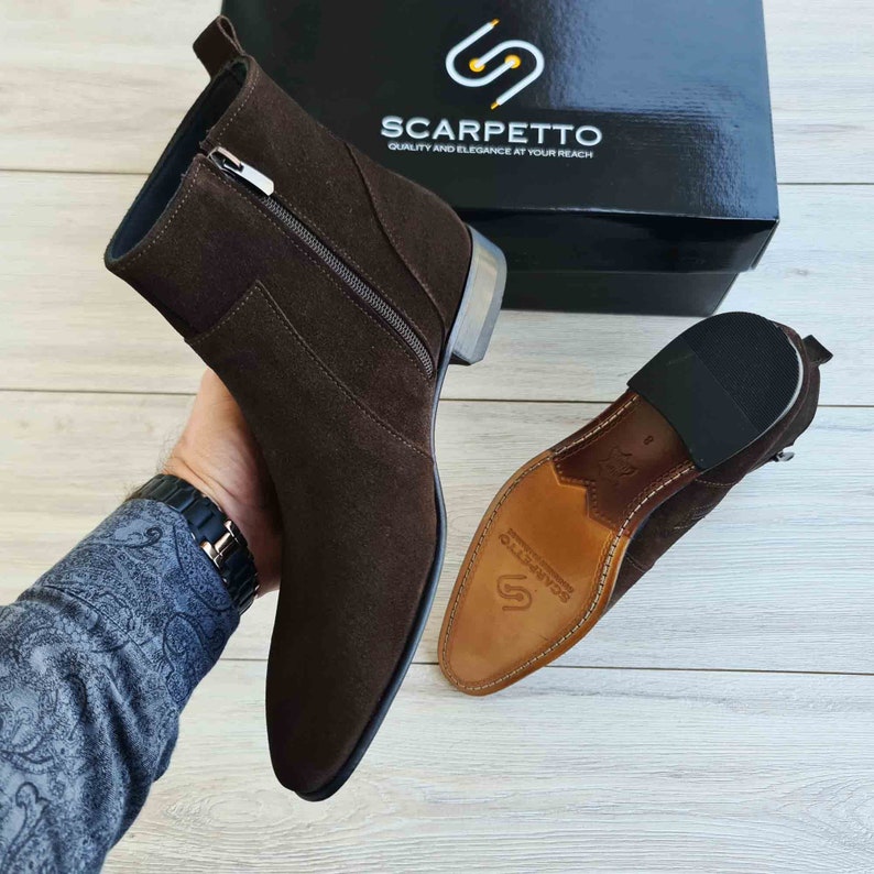 Puede incluir: Botas de tobillo de ante marr&oacute;n con cremallera lateral y suela de goma negra. Las botas est&aacute;n fabricadas por Scarpetto, una marca que destaca por su calidad y elegancia.