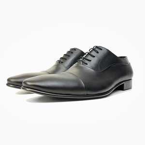 May include: A pair of black leather lace-up shoes with a cap toe design.