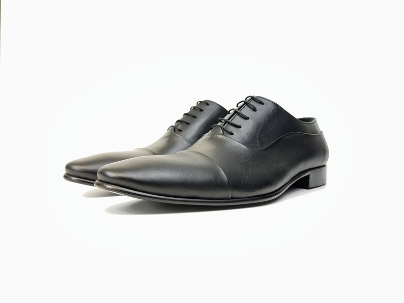 May include: A pair of black leather lace-up shoes with a cap toe design.