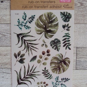 May include: A sheet of rub-on transfers featuring watercolor illustrations of tropical leaves and branches in shades of green. The sheet is labeled "Crafter's Square" and "rub-on transfers".