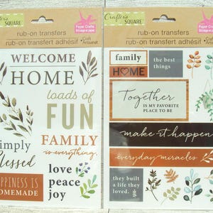 May include: A sheet of rub-on transfers with a home and family theme. The sheet features phrases like "Welcome Home", "Loads of Fun", "Family is Everything", "Simply Blessed", "Happiness is Homemade", "Together is My Favorite Place to Be", "Make it Happen", "Everyday Miracles", and "They Built a Life They Loved".