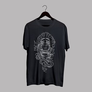 May include: Black t-shirt featuring a white graphic of a woman with a headdress and floral elements. The design is a detailed line drawing, creating a striking contrast against the dark fabric. The shirt is displayed on a hanger.