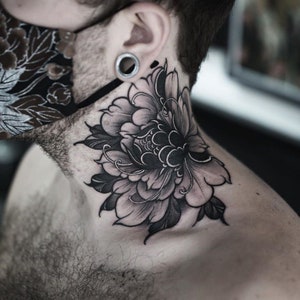 May include: Black and grey ink tattoo of a large flower on a person's neck.