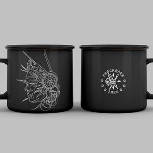 May include: Two black enamel mugs. One mug features a white line drawing of a woman's profile with a decorative headdress. The other mug has the text "PROCREATE INKZ" with a tattoo machine and stars.