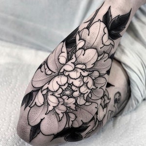 May include: Black and white tattoo of a large peony flower with detailed petals and leaves.