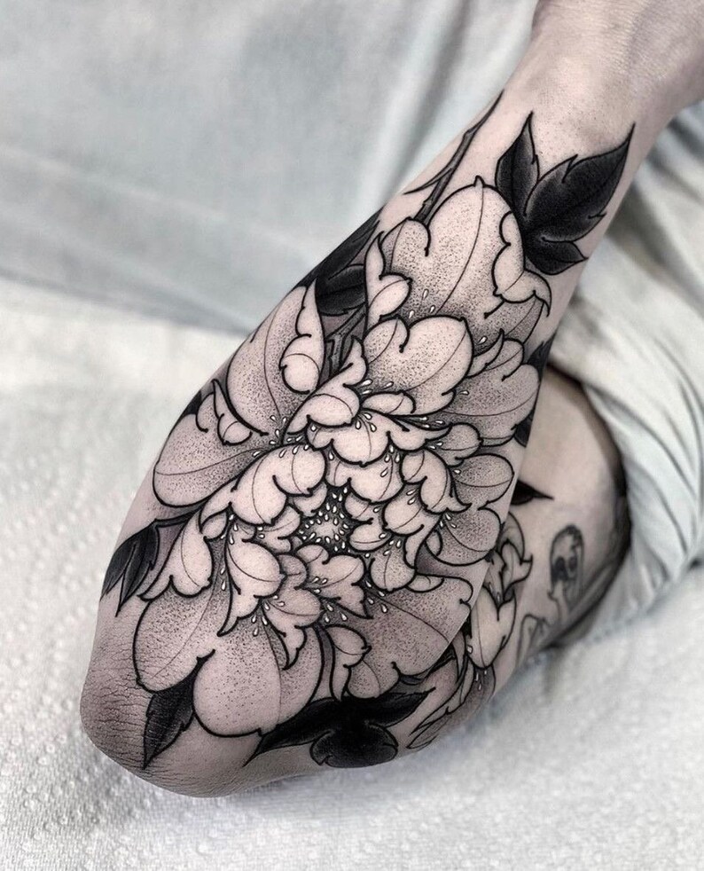 May include: Black and white tattoo of a large peony flower with detailed petals and leaves.
