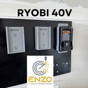 May include: A black wall mount with three gray 3D printed holders for Ryobi 40V batteries. The wall mount is labeled "RYOBI 40V" and has a logo for ENZO 3D SOLUTIONS.