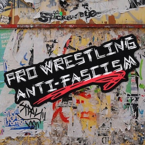 May include: A black sticker with the words "PRO WRESTLING ANTI-FASCISM" in white, outlined letters. A red arrow points to the right. The sticker is on a wall covered in torn posters and graffiti.