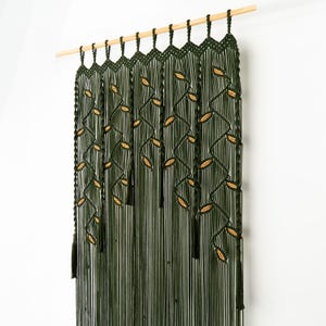 High-quality dark green macrame curtain displaying artisan knot-work and leaf motifs.
