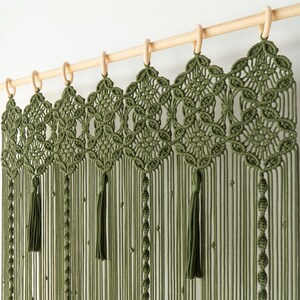 Hand-knotted moss green room divider with a complex diamond and floral pattern at the top.